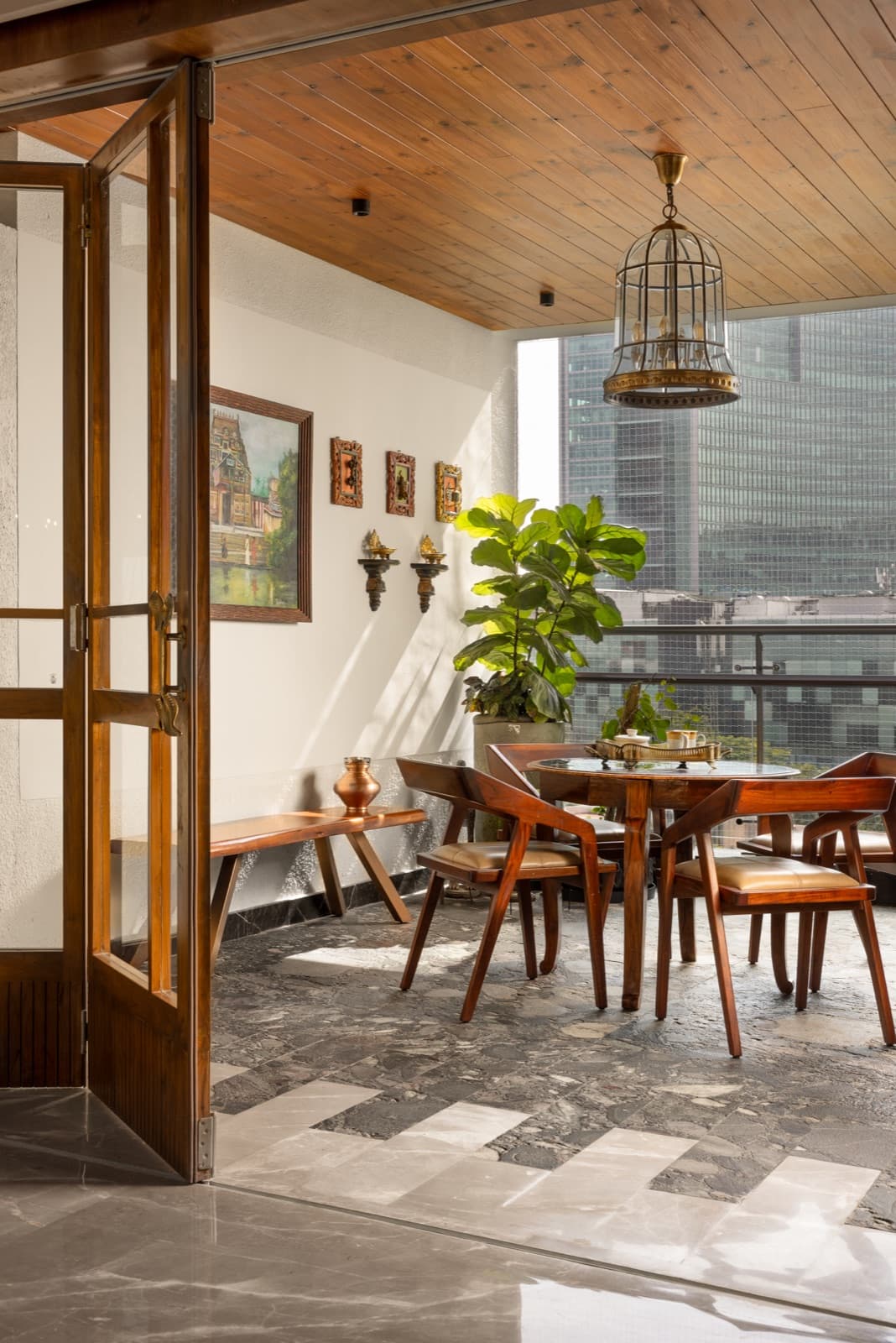 A sunlit dining nook with wood floors, classical art, and a brass birdcage lamp.