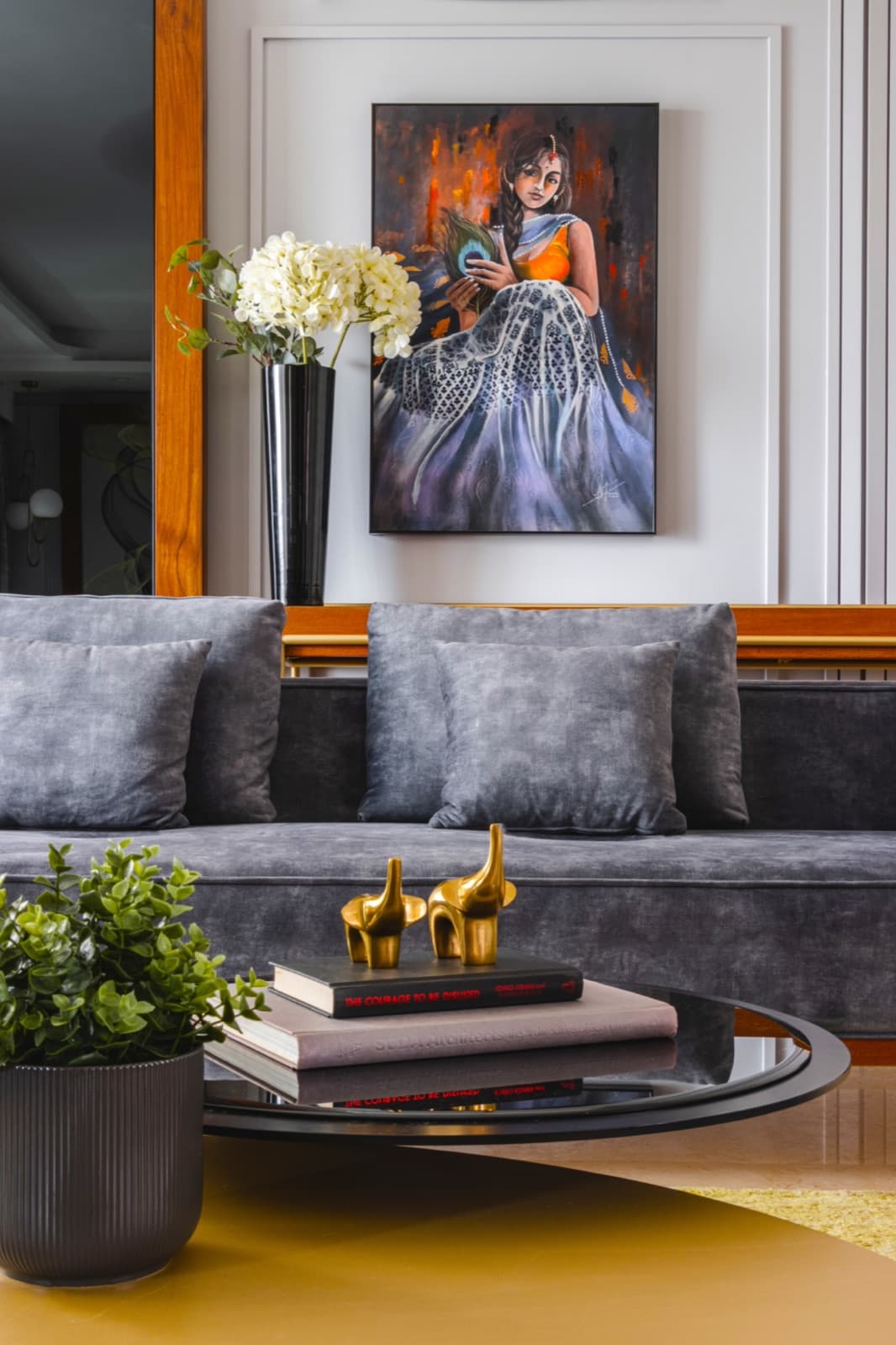 A muted living room with a velvet sofa, traditional artwork, and brass accents.